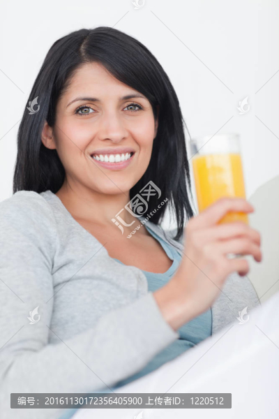 女人微笑著，手里端著滿滿一杯橙汁