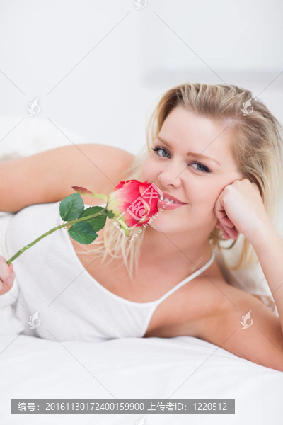 年輕的女人聞著一朵粉紅色的玫瑰
