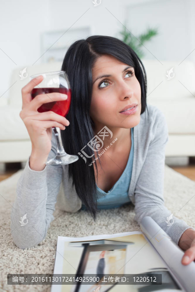 女人拿著一杯紅酒和一本雜志思考