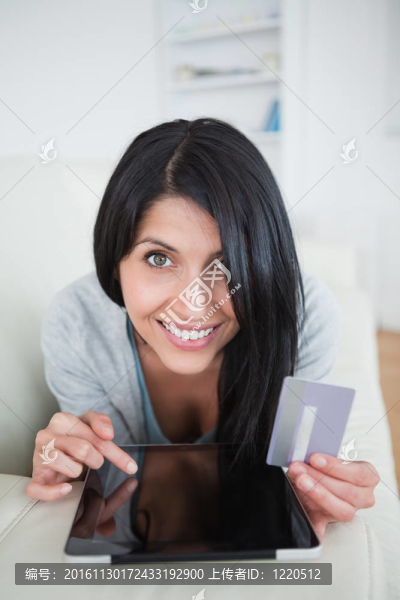 拿著信用卡和觸摸藥片微笑的女人