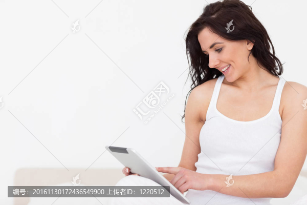 微笑的黑發(fā)女人坐在當(dāng)她用觸摸屏