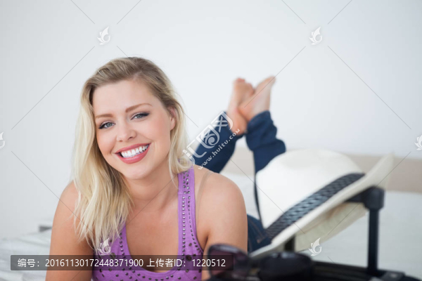 年輕的金發(fā)女郎在一個手提箱后面微笑