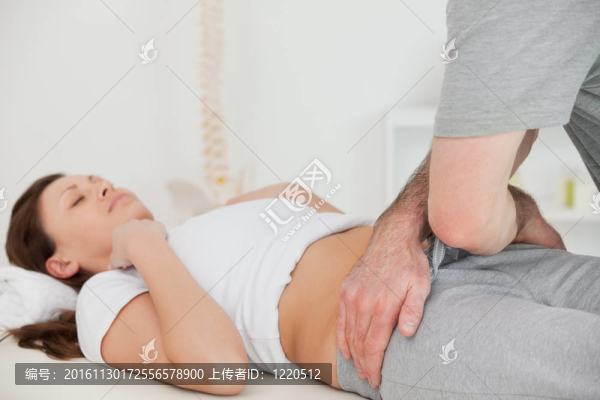黑發(fā)女子躺在一個(gè)物理治療師摸她的臀部