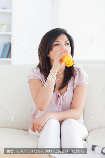 女人坐在沙發(fā)上喝著一杯橙汁