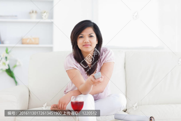 女人坐在沙發(fā)上拿著遙控器