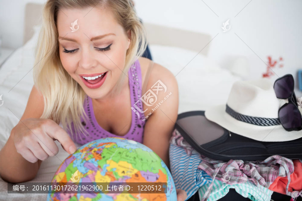 帶著手提箱指著地球儀的女人