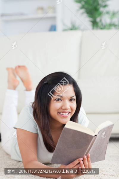 微笑的女人躺在地板上看書