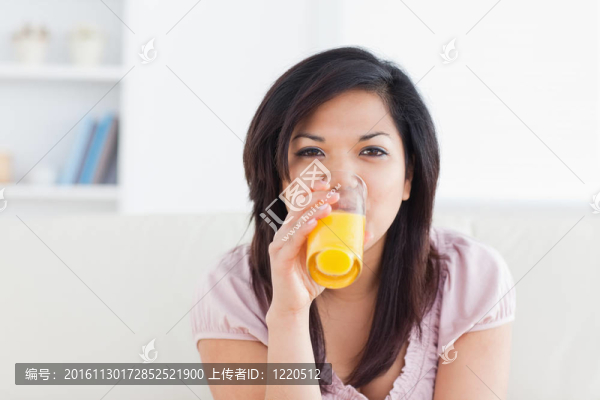 女人一邊喝著橙汁一邊微笑
