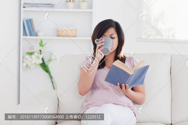 婦女拿著一本書和飲酒