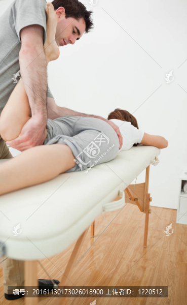 嚴(yán)重的理療師拉伸一個(gè)女人的腿