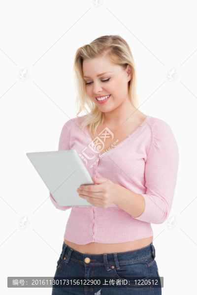微笑金發(fā)女郎站在觸摸她的平板電腦