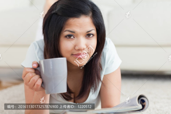 婦女抱著一個杯子在地板上看書