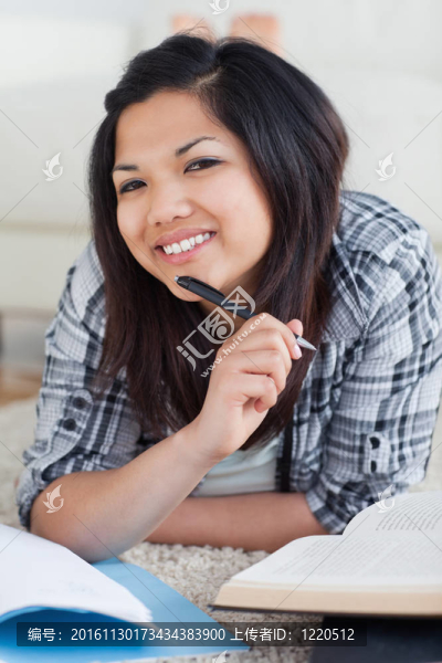 微笑的女人拿著筆躺在地板上