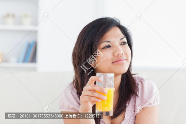 女人微笑著拿著一杯橙汁