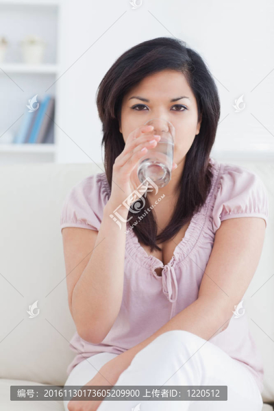 女人坐在沙發(fā)上喝一杯水
