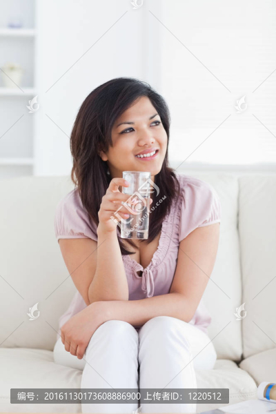 女人坐在沙發(fā)上拿著一杯水
