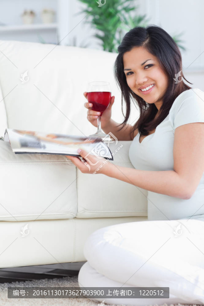 微笑的女人拿著一杯紅酒和一本雜志