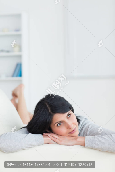 女人坐在沙發(fā)上，頭枕在臂上