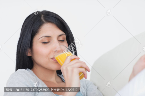 女人在喝一杯橙汁的時候閉上眼睛