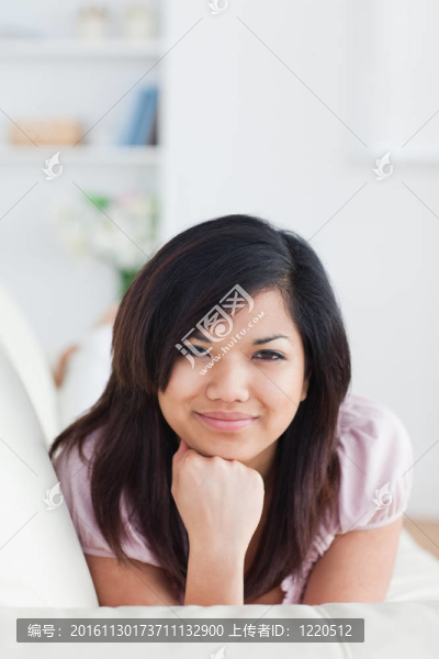 微笑的女人躺在沙發(fā)上，抱著她的頭