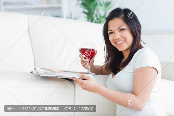 女人跪在地上拿著一杯紅酒和一本雜志