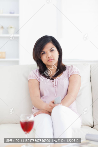 女人坐在沙發(fā)上拿著電視遙控器