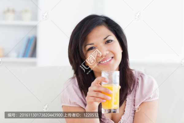 微笑的女人拿著一杯橙汁