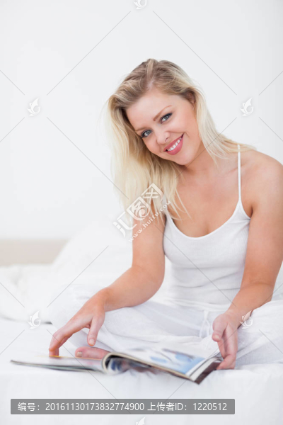 金發(fā)女郎微笑著帶著一本雜志
