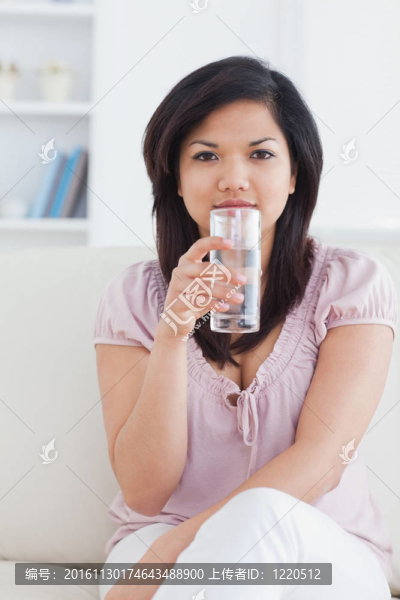 女人坐在沙發(fā)上，拿著一杯水