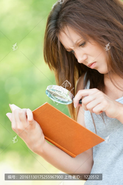 年輕的女人放大鏡以書
