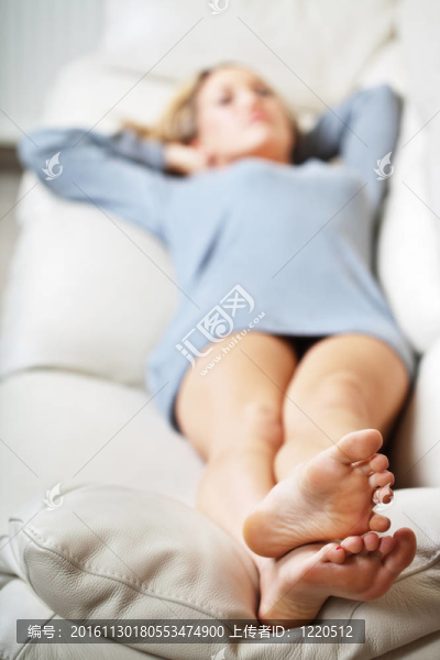 躺在沙發(fā)上的年輕女子；專注于她的腳