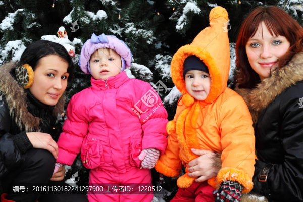 兩個(gè)年輕的女兒和小女兒站在綠樹(shù)的旁邊