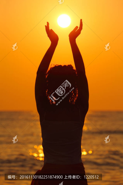 美麗的年輕女子站在海灘上；看日落；手牽著太陽(yáng)