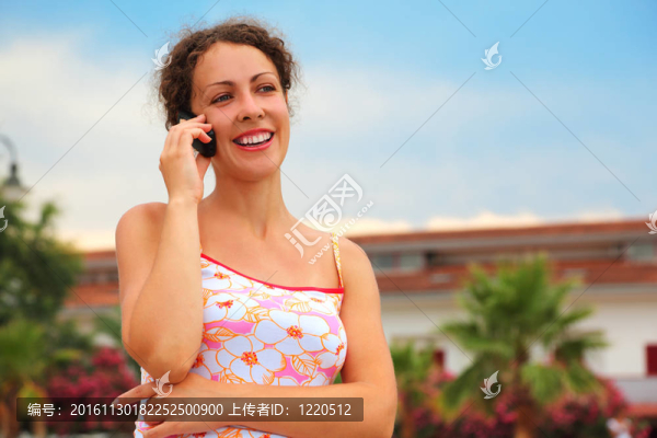 美麗的年輕女子穿著粉紅色的襯衫在手機上微笑
