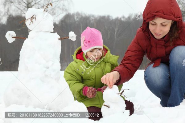 冬天媽媽和女孩在戶外雕塑小雪人
