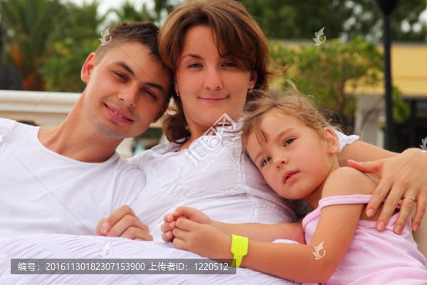 年輕的丈夫和妻子和女兒坐和擁抱，專注于小女孩