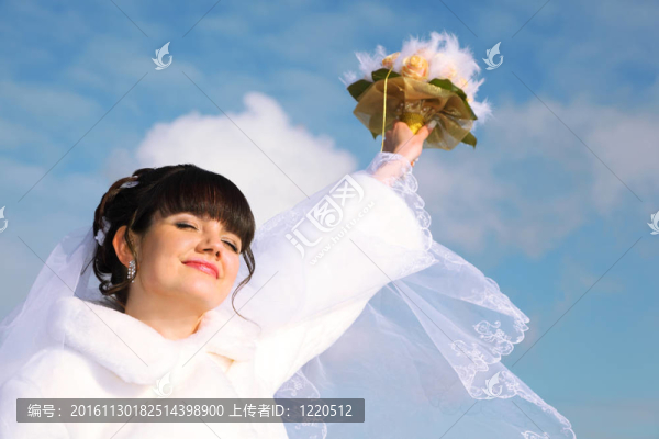 美麗的新娘微笑；閉上眼睛，在冬天的戶外舉起一束玫瑰