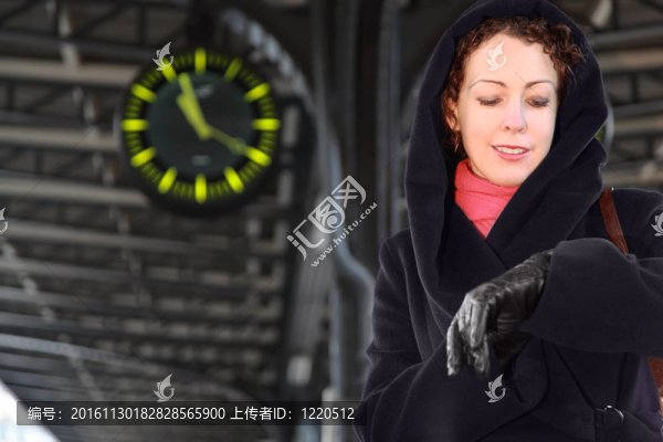 年輕的女人看著她的手表；站在火車站臺。