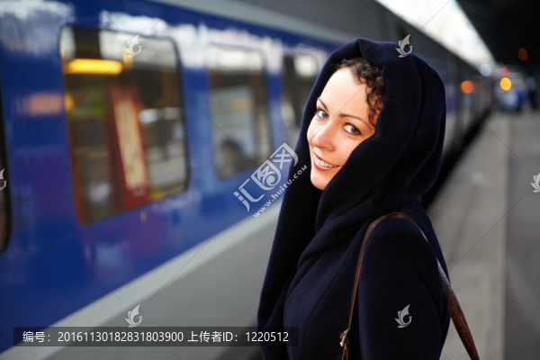 年輕的微笑女子特寫站在站臺附近的火車。