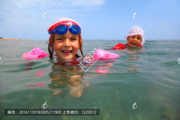 兩個(gè)小姐妹在海里游泳。在藍(lán)色眼鏡里游泳的一個(gè)女孩