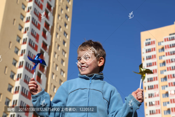 在他的雙手風車藍色上衣的小男孩。多層黃房子背景