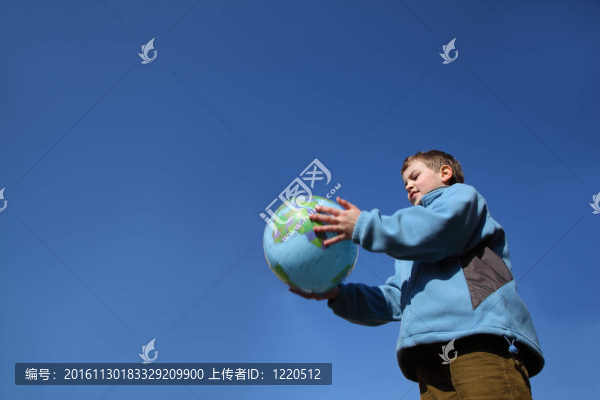 穿著藍(lán)色夾克和棕色褲子的小男孩拿著球形的氣球