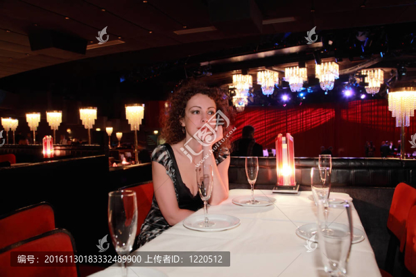漂亮的年輕女子穿著晚禮服坐在餐廳的餐桌旁
