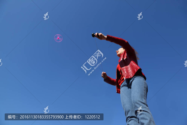 美麗的年輕女子在紅色夾克和藍(lán)色牛仔褲玩粉紅色螺旋槳