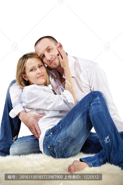 穿著白襯衫和藍(lán)色牛仔褲擁抱的情侶坐在白色的長(zhǎng)毛地毯。