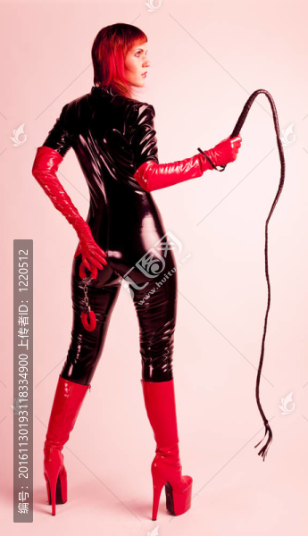 站立的女人穿著奢侈的衣服拿著鞭子和手銬