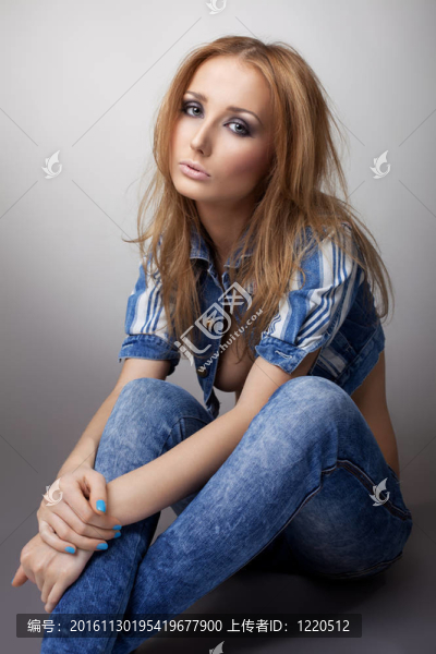 美麗的女孩坐在牛仔褲和夾克