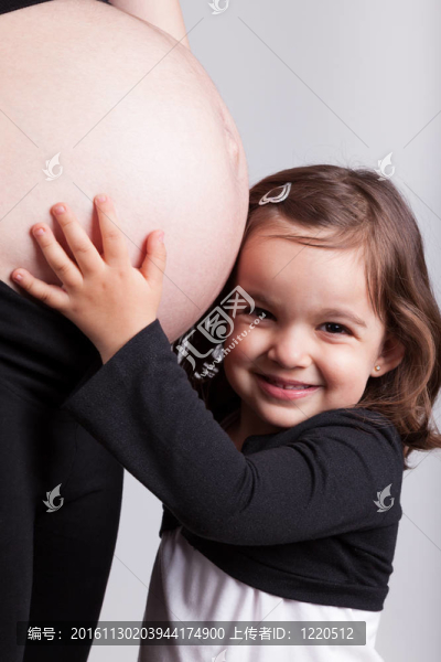 幸福的女兒抱著她懷孕的媽媽肚子