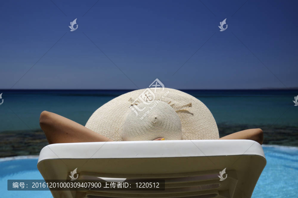 戴著帽子的女人在海面上雙手捂住頭頂