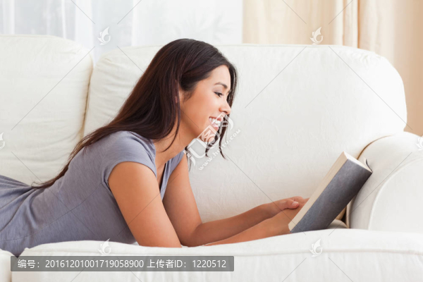躺在沙發(fā)上讀一本書的女人